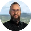 A man with a beard wearing glasses and a black shirt